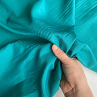 A hand gently wrinkles Longan Craft’s Colorful Cotton Silk Fabric By The Yard, highlighting the lightweight mulberry silk's smooth texture, soft feel, and premium quality—ideal as a breathable silk lining fabric.