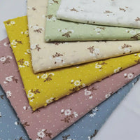 Five folded pieces of Longan Craft Colorful Daisy Print Swiss Dot Fabric—white, green, yellow, pink, and blue—feature small floral prints and dotted Swiss details on breathable 100% cotton.