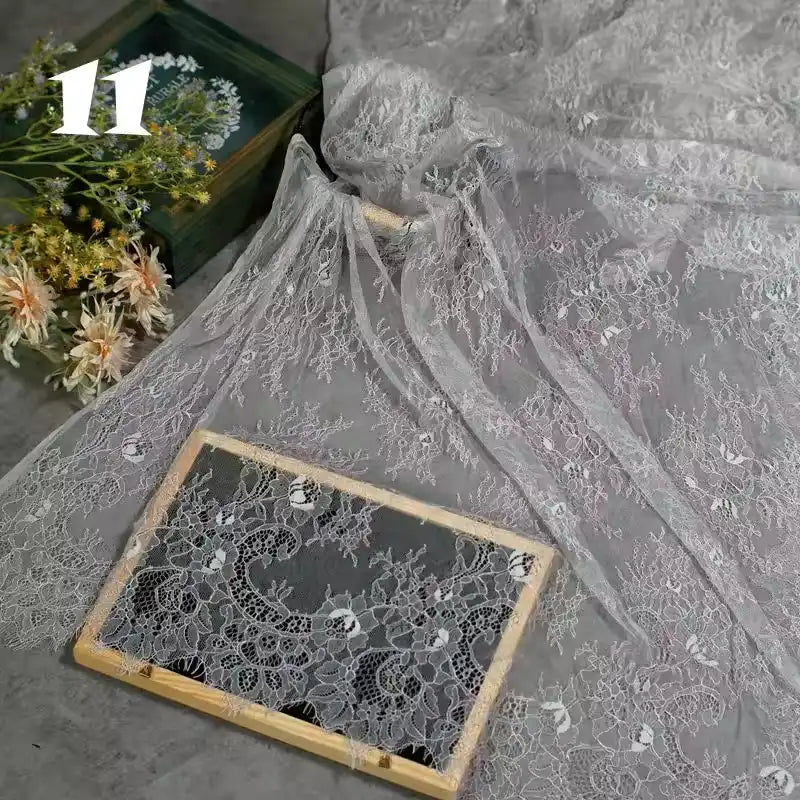 Longan Craft’s Colorful Floral Embroidered Lace Fabric by the yard, with vintage scalloped edges and botanical patterns, is artfully displayed beside a bouquet and wooden frame; the number 11 appears in the top left corner.