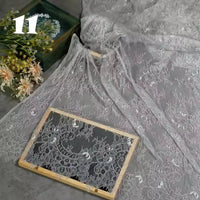 Longan Craft’s Colorful Floral Embroidered Lace Fabric by the yard, with vintage scalloped edges and botanical patterns, is artfully displayed beside a bouquet and wooden frame; the number 11 appears in the top left corner.