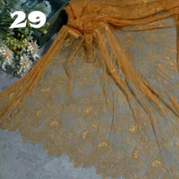 Longan Craft’s Colorful Floral Embroidered Lace Fabric By The Yard, a delicate vintage scalloped lace with botanical patterns, is spread out on a gray surface near white flowers. Number 29 appears in the upper left corner.