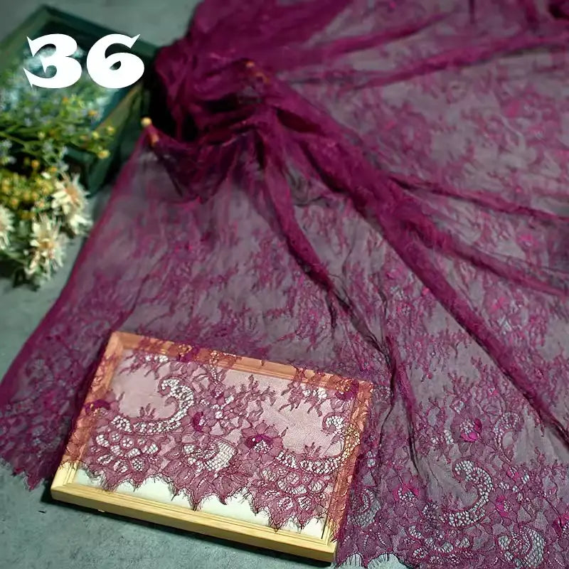 Longan Craft’s Colorful Floral Embroidered Lace Fabric By The Yard, featuring a vintage scalloped botanical pattern, is displayed spread on a surface with some draped over a wooden frame. Number 36 appears in white; flowers are partly visible behind.