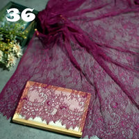 Longan Craft’s Colorful Floral Embroidered Lace Fabric By The Yard, featuring a vintage scalloped botanical pattern, is displayed spread on a surface with some draped over a wooden frame. Number 36 appears in white; flowers are partly visible behind.