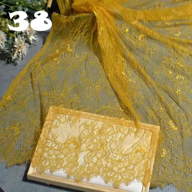 Longan Craft's Colorful Floral Embroidered Lace Fabric is shown spread out in yellow, with a folded piece on a wooden tray. A white “38” appears at the top left, and floral details from this vintage scalloped wedding lace are visible in the background.