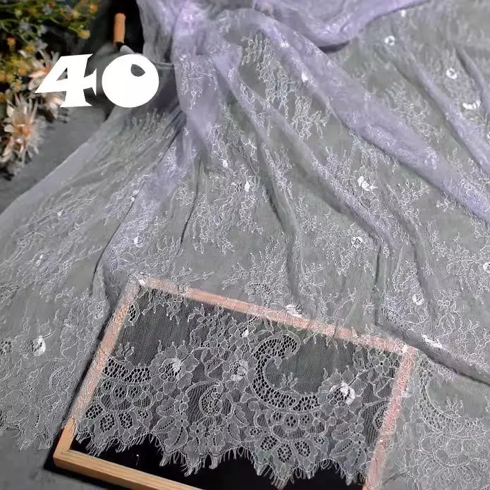 Longan Craft’s Colorful Floral Embroidered Lace Fabric By The Yard, a vintage scalloped lace with botanical patterns, is draped in a wooden frame—ideal for wedding gowns or evening wear. The number 40 appears bold in the upper left corner.