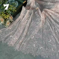 Longan Craft's Colorful Floral Embroidered Lace Fabric, a vintage scalloped material with botanical patterns for wedding gowns, is displayed on a gray surface. A bouquet of white and orange flowers rests in the background. "7" appears in the top left.
