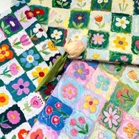 Three folded pieces of Longan Craft Colorful Floral Print Canvas Fabric By The Yard in a grid pattern, topped with a single faux tulip.