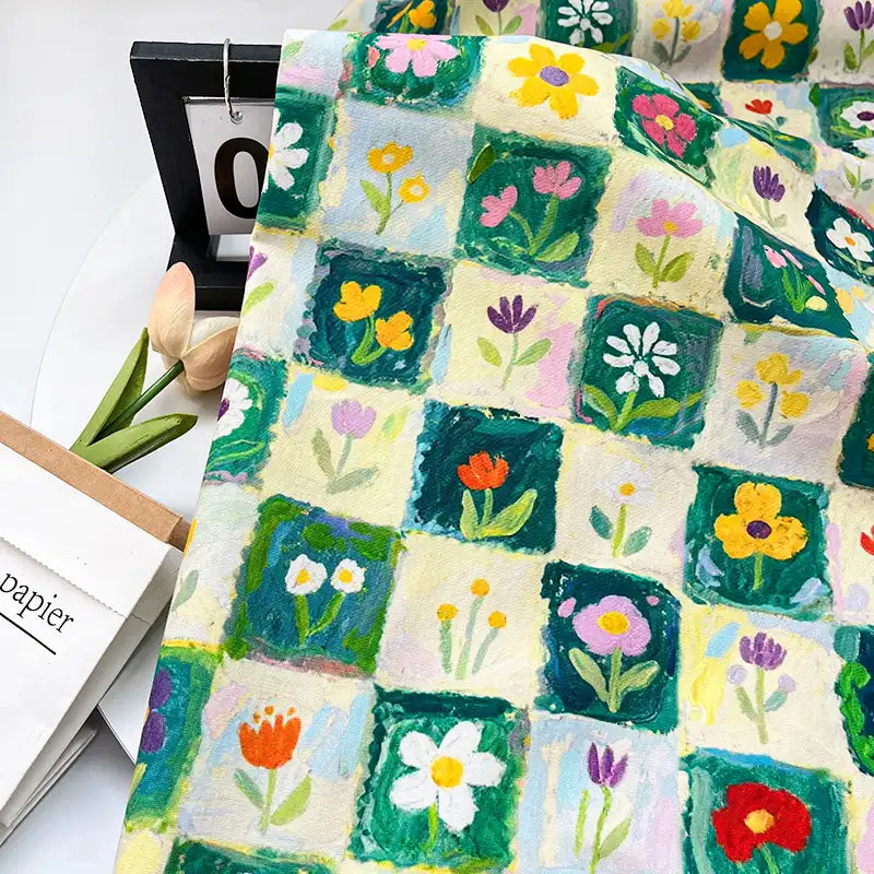 Colorful Floral Print Canvas Fabric By The Yard featuring a grid pattern of squares, each containing a hand-painted style botanical flower illustration in colorful shades of pink, yellow, red, and green.