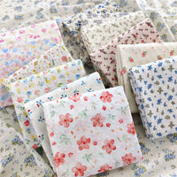 Several stacks of Longan Craft's Colorful Flower Printed Swiss Dot Fabric By The Yard, made from breathable cotton with vibrant floral patterns, are displayed on a surface covered in matching dotted swiss material—perfect for loungewear projects.