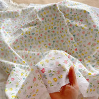 A hand displays Longan Craft's Colorful Flower Printed Swiss Dot Fabric by the yard—a lightweight, semi-transparent cotton material with a dotted floral pattern, ideal for airy loungewear and delicate projects.