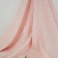 Longan Craft's Colorful Jacquard Damask Fabric by the Yard, featuring a floral pattern and soft folds, is shown draped against a neutral background with a blurred pink flower in the foreground. Ideal for home décor and upholstery projects.