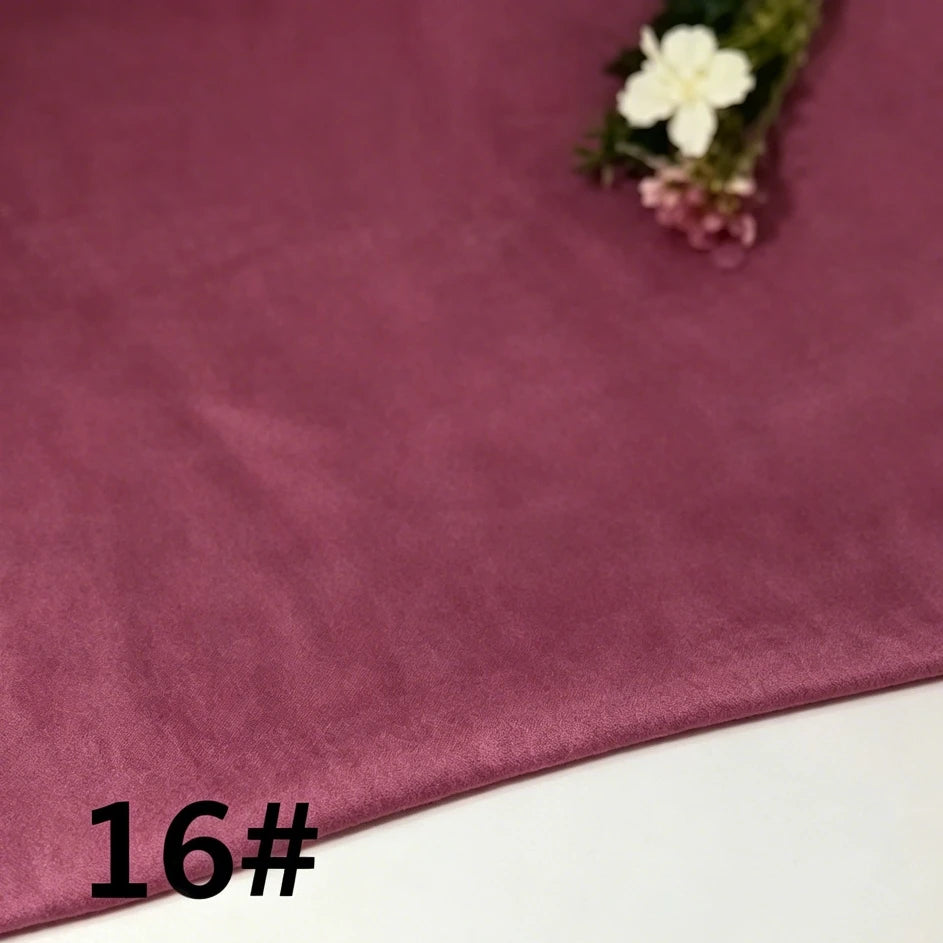 A piece of Longan Craft Colorful Lightweight Ramie Fabric By The Yard in mauve (16#) rests on a surface, accompanied by a small arrangement of white and purple flowers in the top right corner.
