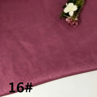 A piece of Longan Craft Colorful Lightweight Ramie Fabric By The Yard in mauve (16#) rests on a surface, accompanied by a small arrangement of white and purple flowers in the top right corner.