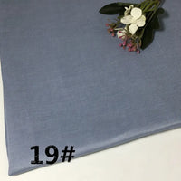 A folded piece of light blue Longan Craft Colorful Lightweight Ramie Fabric by the yard rests on a white surface, marked with the number 19# in black, while artificial flowers decorate one corner.