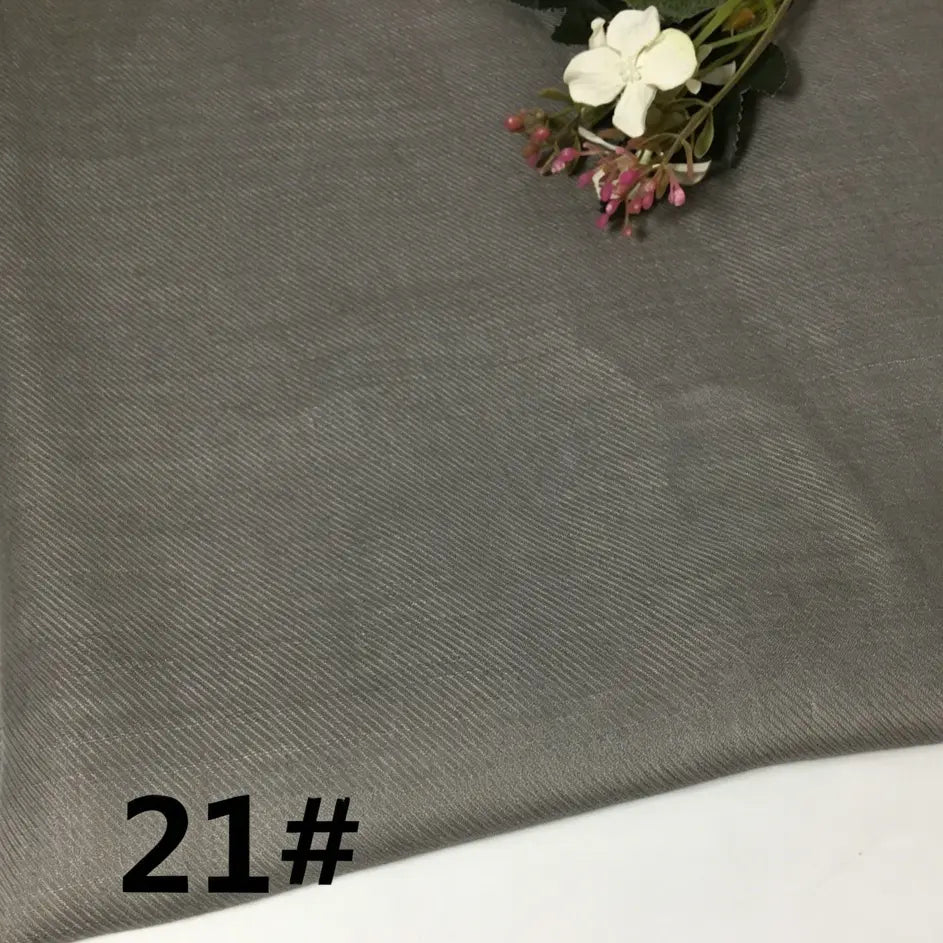 A piece of solid gray Colorful Lightweight Ramie Fabric By The Yard from Longan Craft is displayed flat, showcasing its fine diagonal weave. In the upper right corner, a small bunch of white and purple artificial flowers is placed, while the number 21# appears in bold black in the lower left corner.
