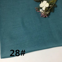 Colorful Lightweight Ramie Fabric By The Yard from Longan Craft in teal blue is displayed flat, with a small floral arrangement placed in the top right corner. The number 28# appears printed in black at the lower left.