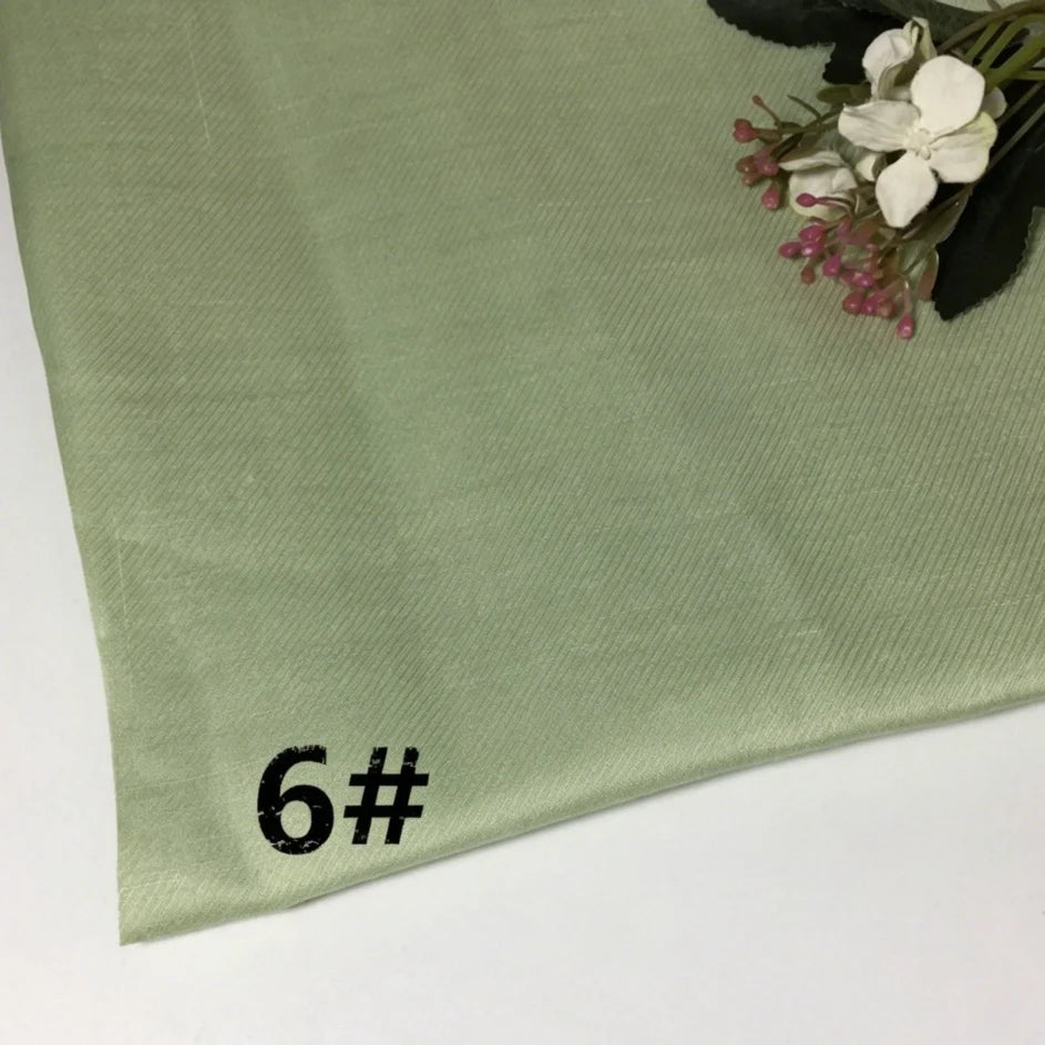A soft, light green Solid Color Pure Ramie Material from Longan Craft features “6#” boldly printed in black at the lower left corner. A small bouquet of artificial flowers is placed on the upper right side of this breathable, lightweight ramie fabric by the yard—perfect for garment making.