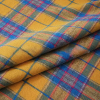 This Colorful One Side Sueded Flannel Fabric By The Yard from Longan Craft showcases a vibrant yellow base with intersecting blue, red, and green yarn-dyed plaid lines that form lively squares across the soft, snuggly surface. Made from cotton and designed for extra comfort, this super snuggle fall flannel features visible folds and a plush texture that enhances its colorful, energetic appearance.