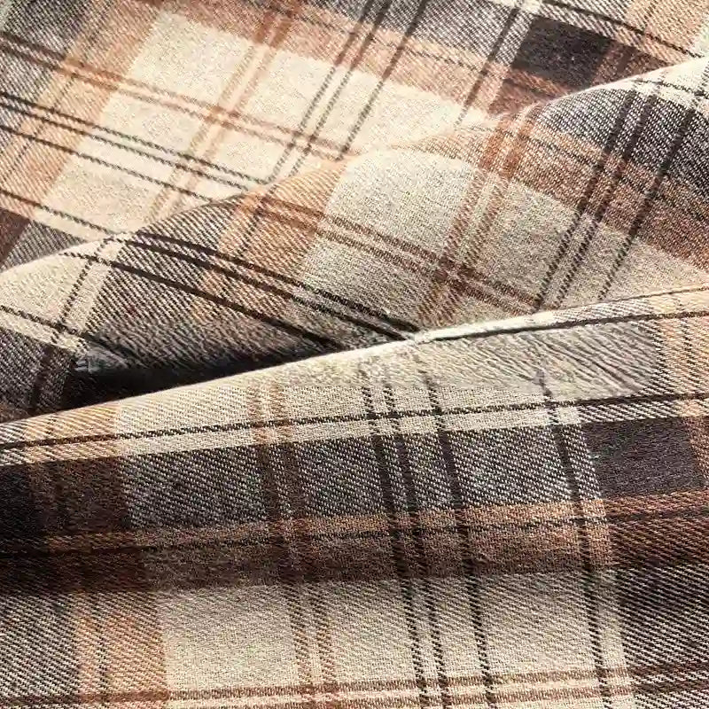 Close-up of the Colorful One Side Sueded Flannel Fabric By The Yard from Longan Craft, featuring intersecting lines in brown and beige yarn-dyed plaid, highlighting the soft, textured folds of this super snuggle cotton flannel material.