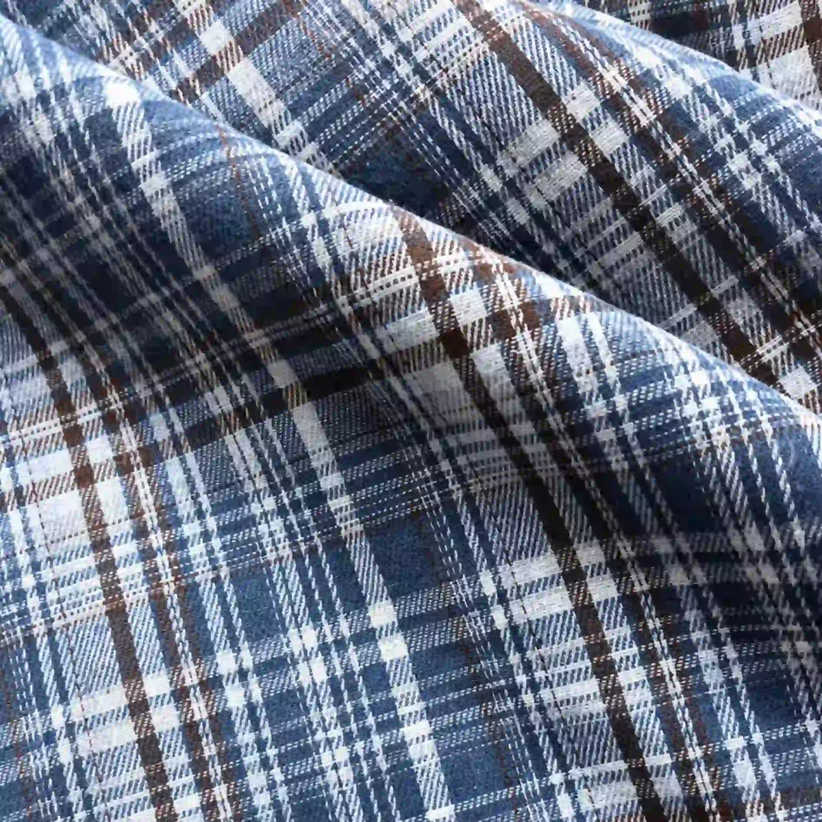 Close-up of the Longan Craft Colorful One Side Sueded Flannel Fabric By The Yard, a yarn dyed cotton plaid flannel featuring intersecting blue, white, and brown lines. Soft folds highlight the super snuggle fall flannel material’s detailed texture and pattern.