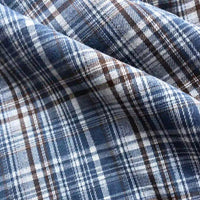 Close-up of the Longan Craft Colorful One Side Sueded Flannel Fabric By The Yard, a yarn dyed cotton plaid flannel featuring intersecting blue, white, and brown lines. Soft folds highlight the super snuggle fall flannel material’s detailed texture and pattern.