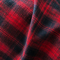 Close-up of Longan Craft Colorful One Side Sueded Flannel Fabric by the yard, featuring a red and black yarn dyed cotton plaid pattern with a diagonal crease that highlights the super snuggle brushed texture and intersecting lines.