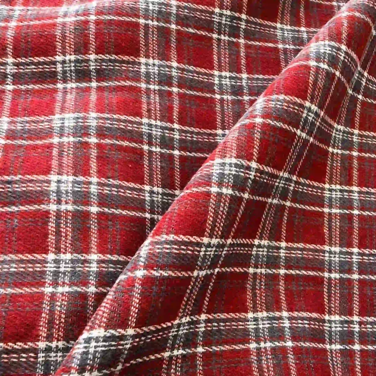 Colorful One Side Sueded Flannel Fabric By The Yard from Longan Craft features a yarn-dyed cotton plaid design with white, black, and yellow lines on a red background forming a classic checkered pattern. Slight folds highlight this Super Snuggle Fall Flannel Material’s soft texture, brushed sueded finish, and substantial thickness.