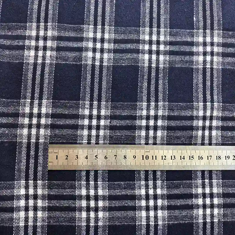 A metal ruler placed on Longan Craft’s Colorful One Side Sueded Flannel Fabric By The Yard—a yarn dyed cotton plaid flannel—shows a close-up of the blue and white pattern and scale in centimeters.