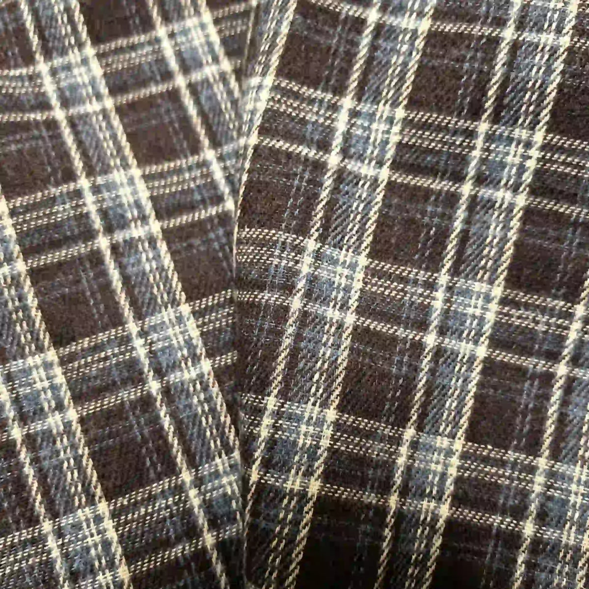 Close-up of two pieces of Longan Craft Colorful One Side Sueded Flannel Fabric By The Yard, featuring a black, white, and blue yarn-dyed cotton plaid pattern that highlights the soft texture and intersecting lines of this super snuggle fall material.