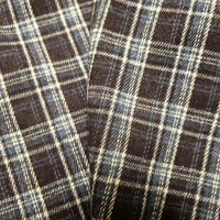 Close-up of two pieces of Longan Craft Colorful One Side Sueded Flannel Fabric By The Yard, featuring a black, white, and blue yarn-dyed cotton plaid pattern that highlights the soft texture and intersecting lines of this super snuggle fall material.
