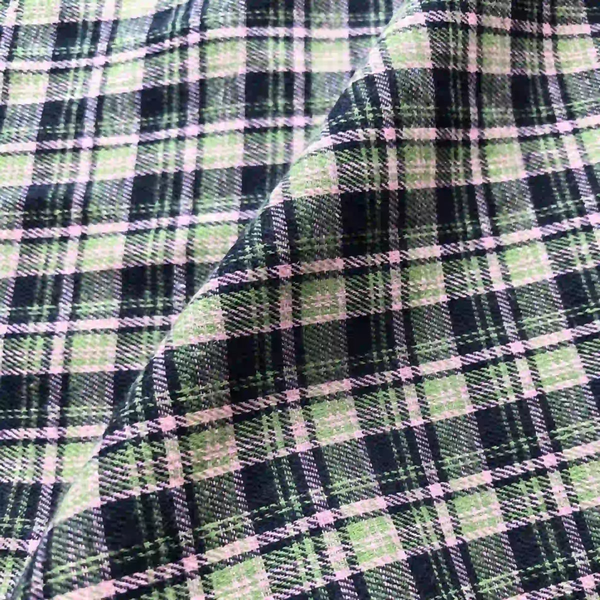 Close-up of Longan Craft’s Colorful One Side Sueded Flannel Fabric By The Yard, a yarn dyed cotton plaid from the Super Snuggle Fall collection, featuring green, black, and white checks with a diagonal fold that casts a shadow and enhances the fabric’s textured appearance.