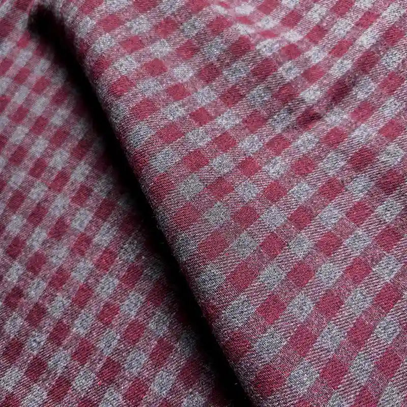 Close-up of Longan Craft’s Colorful One Side Sueded Flannel Fabric By The Yard, a yarn dyed cotton plaid featuring a red and gray checkered pattern with visible texture and folds. The super snuggle fall flannel material displays small squares arranged in a regular grid.