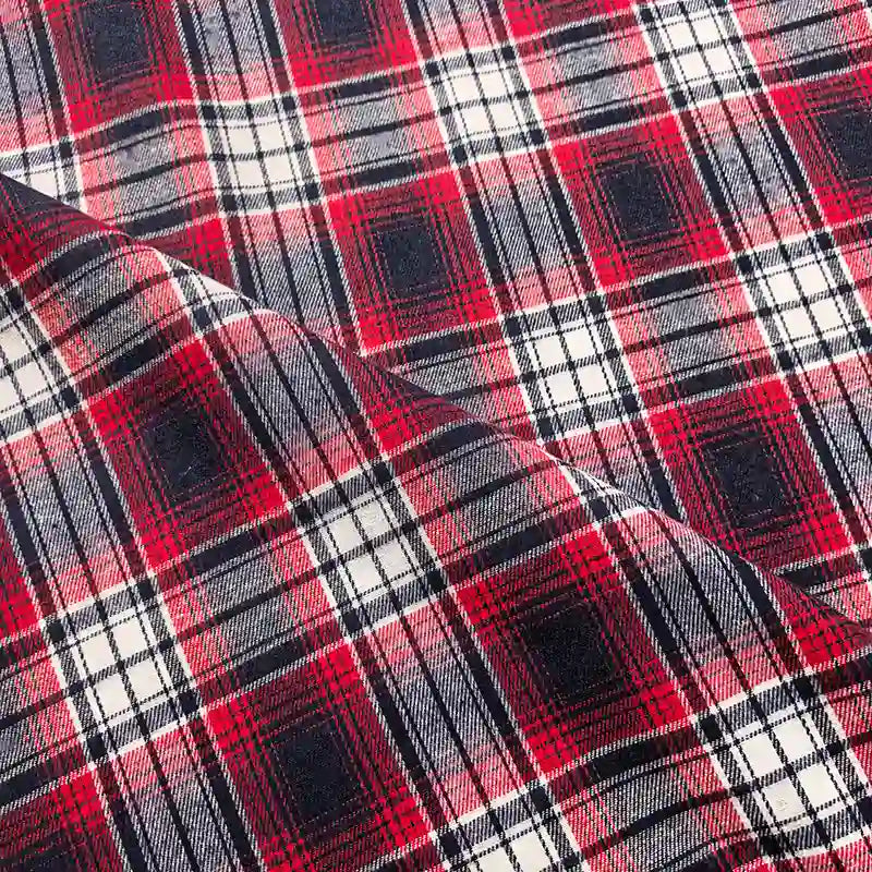 Close-up of the Longan Craft Colorful One Side Sueded Flannel Fabric By The Yard, a yarn dyed cotton plaid material, in shades of red, white, and black. The image features a diagonal fold that showcases the soft sueded texture and detailed woven pattern of this Super Snuggle Fall Flannel.