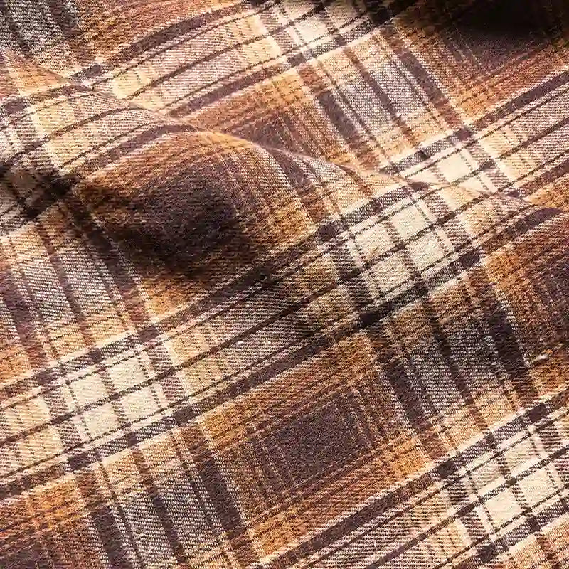 Close-up of Longan Craft Colorful One Side Sueded Flannel Fabric by the Yard, featuring a soft, textured appearance with visible folds in a yarn-dyed brown, beige, and white plaid pattern—perfect for snuggly fall projects.