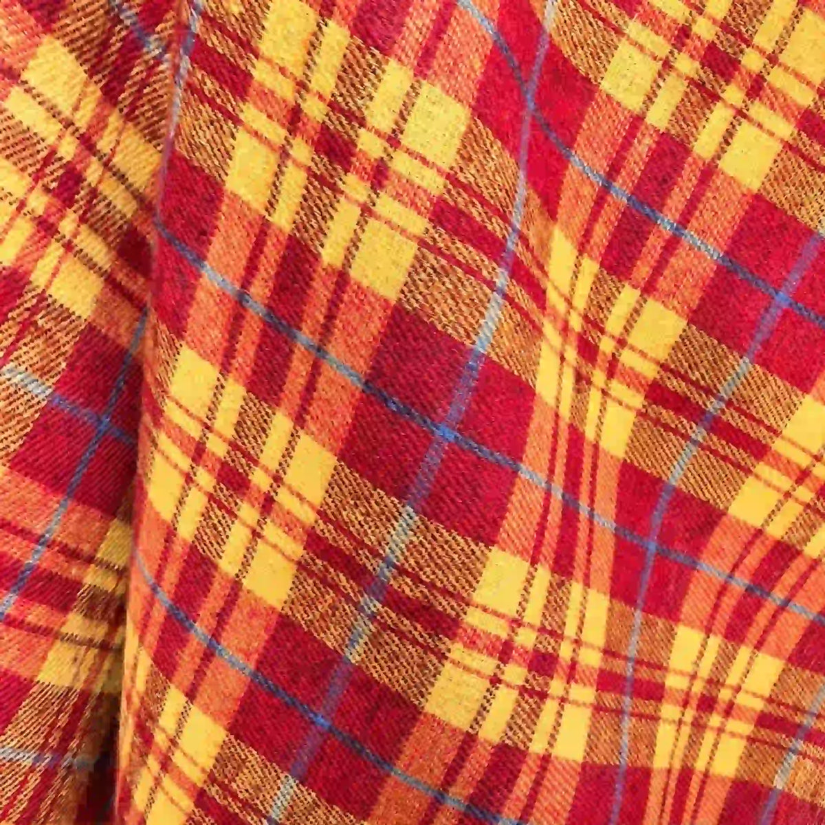 A detailed view of Longan Craft’s Colorful One Side Sueded Flannel Fabric by the yard shows vibrant yarn-dyed cotton plaid in shades of red, yellow, and orange with blue intersecting lines, creating a striking checkered pattern—perfect for super snuggly fall projects.
