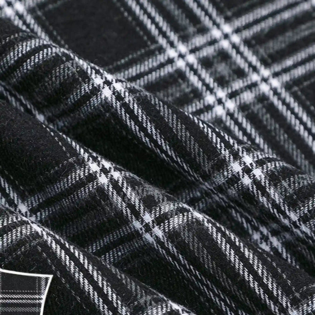 Close-up of the “Colorful One Side Sueded Flannel Fabric By The Yard” by Longan Craft, a yarn dyed cotton plaid flannel fabric. The super snuggle fall material features a black and white checkered pattern with visible texture and softness, highlighted by gentle folds in the fabric.