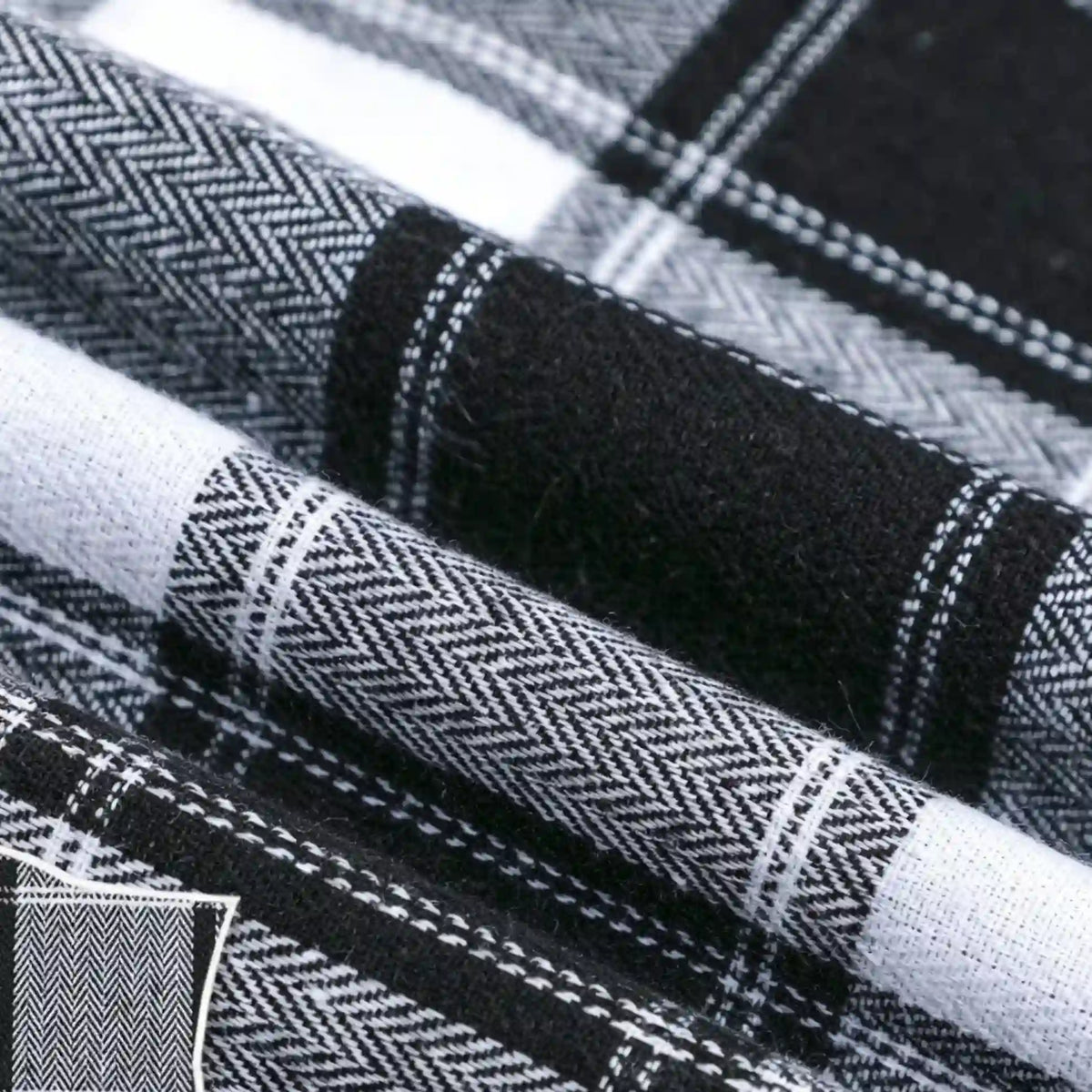 Close-up of Longan Craft’s Colorful One Side Sueded Flannel Fabric by the yard, a yarn dyed cotton plaid flannel from their Super Snuggle Fall collection, showing black, white, and gray woven patterns with herringbone and solid sections for enhanced texture and detail.