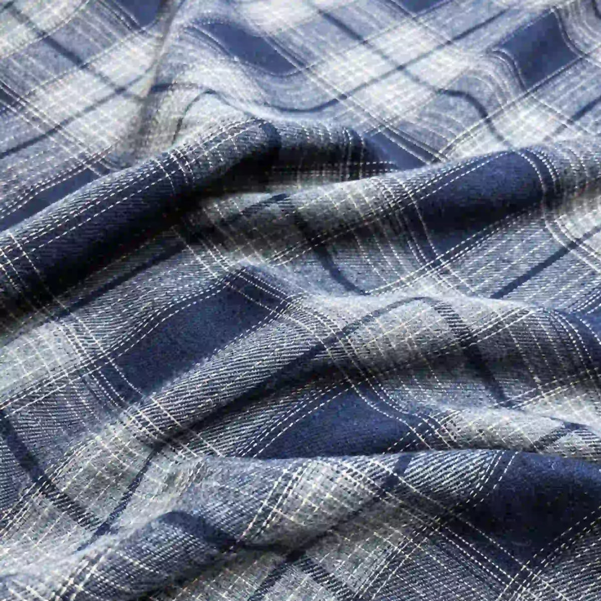 Close-up of Longan Craft Colorful One Side Sueded Flannel Fabric By The Yard, a yarn-dyed cotton plaid flannel featuring intersecting lines and squares in varying blue and white shades. Soft folds highlight the brushed, super snuggle texture of this fall-ready fabric.