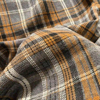 Close-up of the Colorful One Side Sueded Flannel Fabric By The Yard from Longan Craft, a yarn dyed cotton plaid flannel fabric featuring a soft, textured surface and a cozy appearance. This super snuggle fall material showcases a classic plaid pattern in shades of gray, brown, white, and black.
