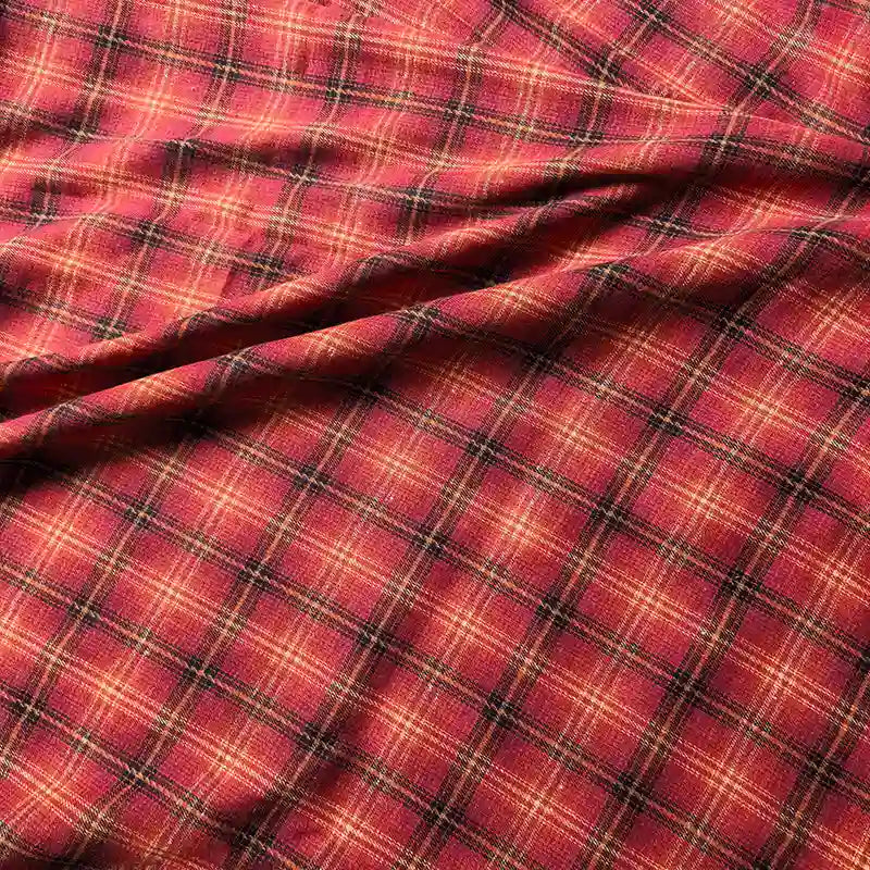 The Colorful One Side Sueded Flannel Fabric By The Yard from Longan Craft features a red, yellow, and black yarn-dyed plaid pattern with intersecting lines. This super snuggle fall flannel material showcases visible folds and a soft, sueded texture, making it perfect for cozy projects.