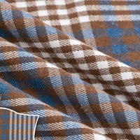 The Colorful One Side Sueded Flannel Fabric by the Yard from Longan Craft features a yarn-dyed cotton plaid design in brown, white, and blue, with a soft sueded finish. Shown here in gentle folds and close-up detail, this Super Snuggle Fall Flannel showcases its woven texture and intersecting checkered lines.