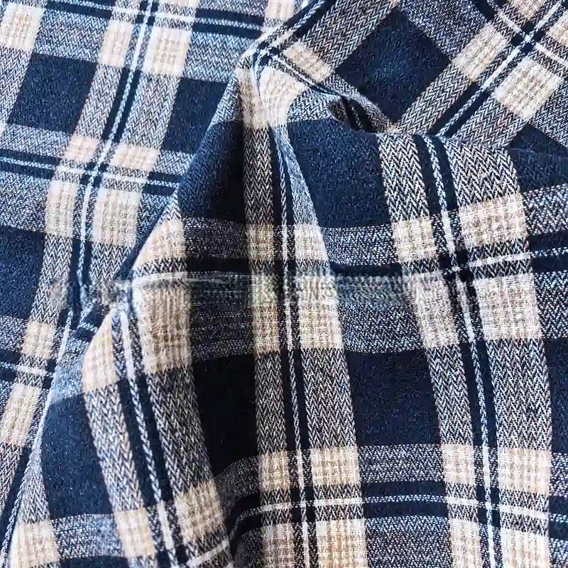 Close-up of the Colorful One Side Sueded Flannel Fabric by Longan Craft, featuring intersecting blue, white, and black yarn-dyed plaid lines and a crumpled texture characteristic of super snuggle cotton flannel material.