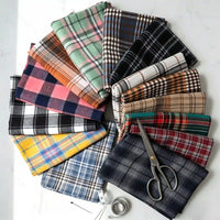 A selection of vibrant Longan Craft Colorful One Side Sueded Flannel Fabric By The Yard, featuring yarn-dyed cotton plaid designs from the Super Snuggle Fall Flannel collection, is displayed in a circular arrangement with scissors, a tape measure, and pins on a white surface.