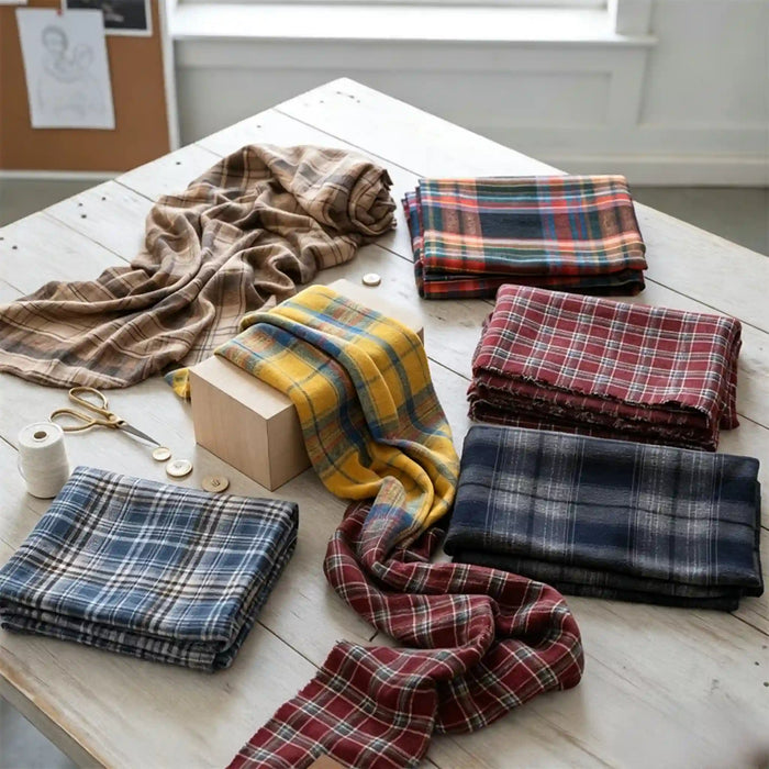 A selection of Colorful One Side Sueded Flannel Fabric By The Yard from Longan Craft, featuring yarn dyed cotton plaid and super snuggle fall flannel material, is neatly folded and arranged on a rustic white wooden table, surrounded by sewing supplies such as scissors, buttons, a spool of thread, and a wooden block.