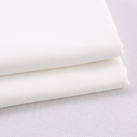 Two pieces of Longan Craft Colorful Rayon Polyester Blend Gabardine Fabric, heavyweight viscose gabardine material perfect for DIY uniforms, are stacked on a white textured surface.