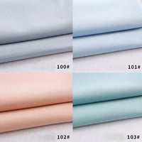 Four neatly folded pieces of Longan Craft Colorful Rayon Polyester Blend Gabardine Fabric—light gray (100#), light blue (101#), pale peach (102#), and mint green (103#)—are displayed separately on a white background.