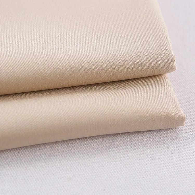 Two neatly folded pieces of Longan Craft's Colorful Rayon Polyester Blend Gabardine Fabric, a heavyweight viscose gabardine textile perfect for DIY uniforms, stacked on a pale, slightly textured surface.