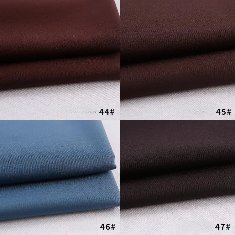 Four swatches of Longan Craft's Colorful Rayon Polyester Blend Gabardine Fabric are shown: dark brown (44#), medium brown (45#), light blue (46#), and very dark brown (47#)—each neatly folded on a white surface.