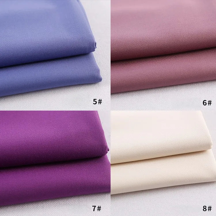 Four folded Longan Craft gabardine fabrics by the yard in light purple, mauve, dark purple, and off-white are stacked on a light background, showcasing the appeal of this colorful rayon polyester blend—perfect for DIY uniforms.