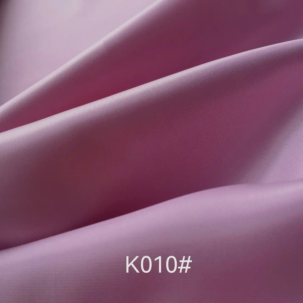 Close-up of smooth, folded light purple Colorful Satin Viscose Fabric by Longan Craft, featuring a soft sheen and twill weave. The centered text "K010#" appears at the bottom of the image. Ideal for formal dresses and garments.